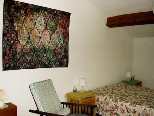 - une chambre avec un lit, une chaise et un tableau mural dans l'établissement Domaine De Luzenac, à Fa