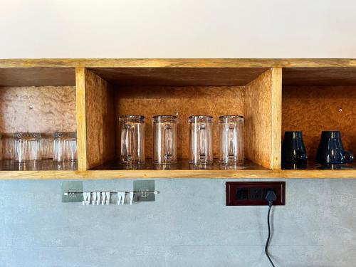a row of glasses sitting on a wooden shelf at Mermaid Island Beach Resorts in Puducherry
