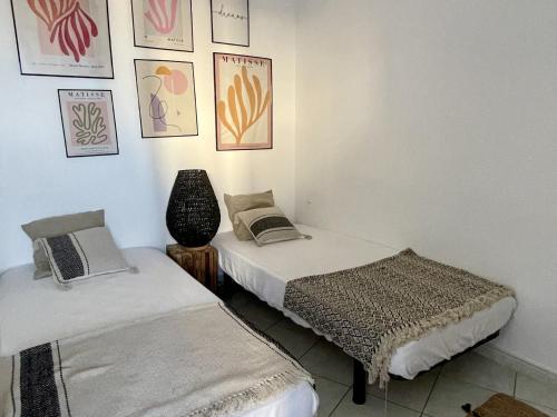 deux lits dans une chambre avec des tableaux au mur dans l'établissement Appartement rénové avec piscine commune, 4 couchages, climatisé, wifi, terrasse vue mer - FR-1-748-3, à Canet
