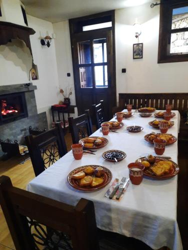 a table with plates of food on it with a fireplace at ЧОЛАКОВАТА КЪЩА in Koprivshtitsa