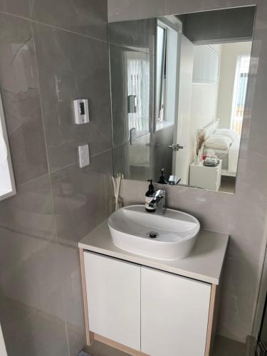 uma casa de banho com um lavatório branco e um espelho. em Private Ensuite for singles or couples em Auckland