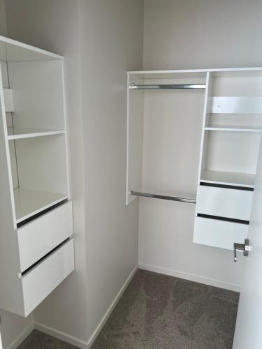 a white walk in closet with white shelves at Private Ensuite for singles or couples in Auckland