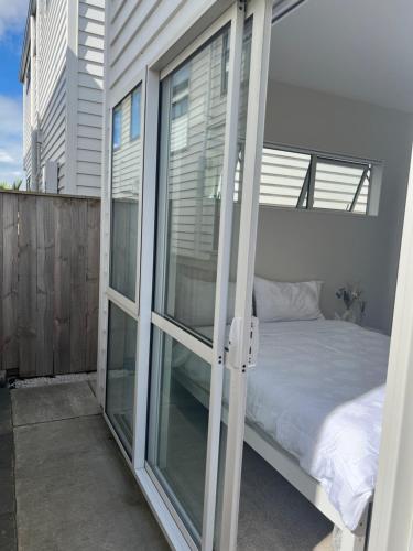sypialnia z łóżkiem i przesuwnymi szklanymi drzwiami w obiekcie Private Ensuite for singles or couples w Auckland