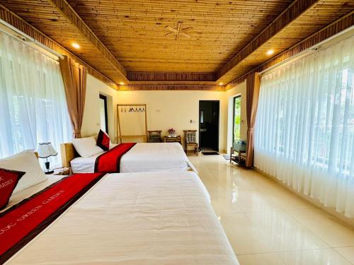 two beds in a large room with windows at Tam Coc Green Garden Bungalow in Ninh Binh