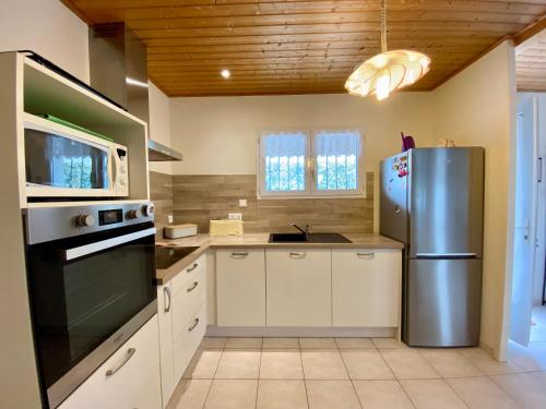 une cuisine avec un réfrigérateur en acier inoxydable et un micro-ondes dans l'établissement Maison 3 chambres (5 pers) à 400m de la plage avec jardin clos, parking & WIFI à Brétignolles-sur-Mer - FR-1-231-323, à Bretignolles-sur-Mer