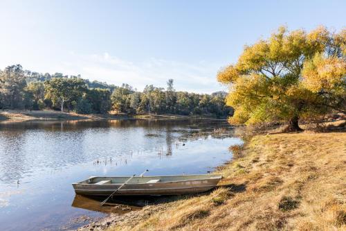 a boat sitting on the shore of a lake at Rolling Oaks Ranch - 200 Acres of Lakeside Beauty & Countryside Serenity in Mariposa
