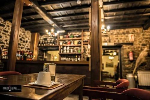 a restaurant with a wooden table and chairs and a bar at Hotel Rural Palacio de Galceran in Sotiello