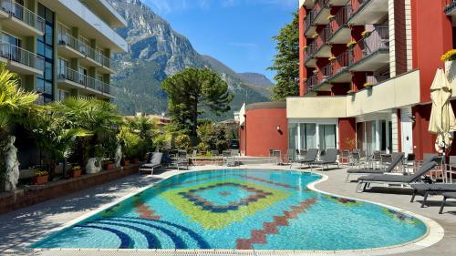 una piscina del resort con una montagna sullo sfondo di Hotel Royal a Riva del Garda