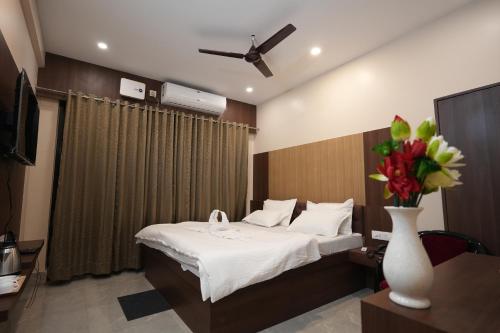 a hotel room with a bed and a vase of flowers at Hotel New Sagar Priya in Digha