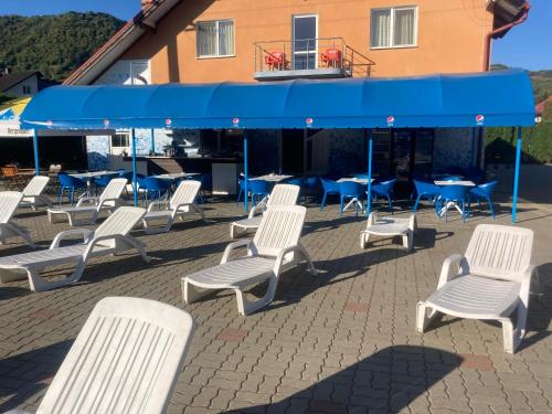 a group of white chairs and tables and blue umbrellas at Pensiunea Hyperion Cormaia in Sîngeorz-Băi