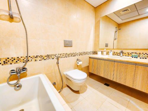 a bathroom with a toilet and a tub and a sink at NA 303 Ansam Yas Island in Abu Dhabi