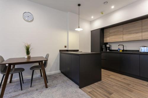 a kitchen with black cabinets and a table and chairs at Fantastic 1 Bedroom Apartment in Bolton in Bolton