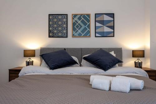 Fantastic 1 Bedroom Apartment in Bolton في بولتون: غرفة نوم بسريرين مع وسائد زرقاء وبيضاء
