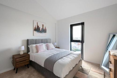 a white bedroom with a bed and a window at Beautiful 2 bedroom apartment in a converted mill in Leeds