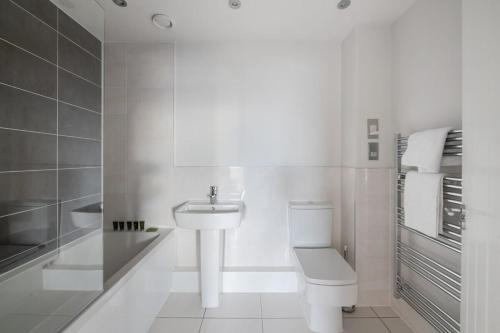 a white bathroom with a toilet and a sink at Beautiful 2 bedroom apartment in a converted mill in Leeds