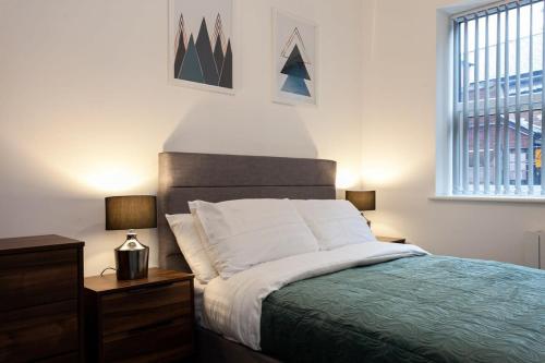a bedroom with a bed and two lamps and a window at Fantastic 1 bedroom apartment in Bolton in Bolton