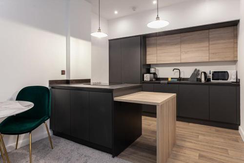 a kitchen with black cabinets and a table and chairs at Fantastic 1 bedroom apartment in Bolton in Bolton