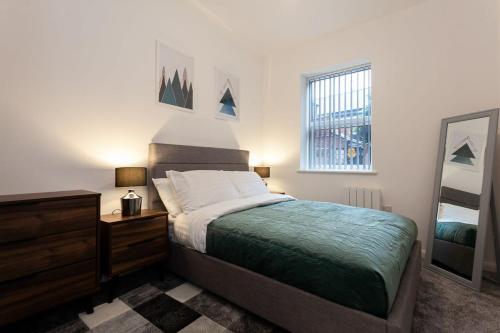 a bedroom with a bed and a dresser and a mirror at Fantastic 1 bedroom apartment in Bolton in Bolton