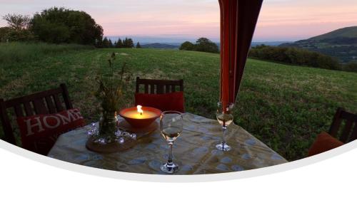 a table with a candle and two wine glasses on a field at Retro Caravan with Mountain Views in Abergavenny