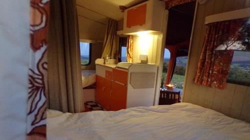 Habitación pequeña con cama y nevera. en Retro Caravan with Mountain Views en Abergavenny
