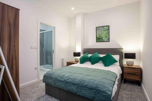 a bedroom with a large bed with green pillows at Modern & Stylish 1 Bedroom Apartment in Bolton in Bolton