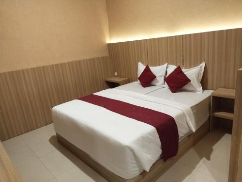 a bedroom with a large white bed with red pillows at Hotel Kembang Joyo in Palu