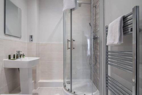 baño blanco con ducha y lavamanos en Lovely Riverside 2 Bed Apartment, en Leeds