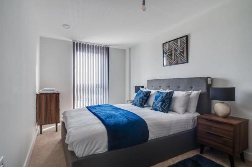 a bedroom with a large bed with blue pillows at Lovely Riverside 2 Bed Apartment in Leeds