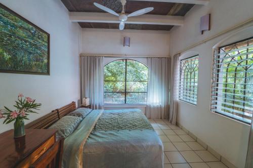 1 dormitorio con 1 cama y ventilador de techo en Gaia's Garden Guest House, en Auroville