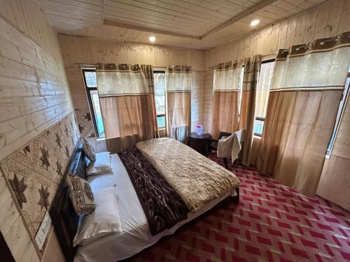 ein Schlafzimmer mit einem Bett in einem Zimmer mit Fenstern in der Unterkunft Forest inn in Pahalgām