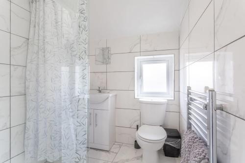 a white bathroom with a toilet and a window at Lovely 2 Bed apartment close to city centre in Bradford
