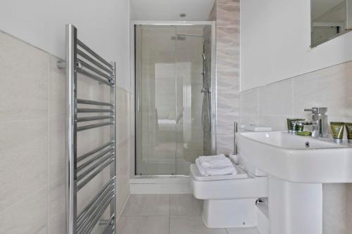 a white bathroom with a sink and a shower at Spacious 1 Bedroom Apartment in a Converted Mill in Leeds