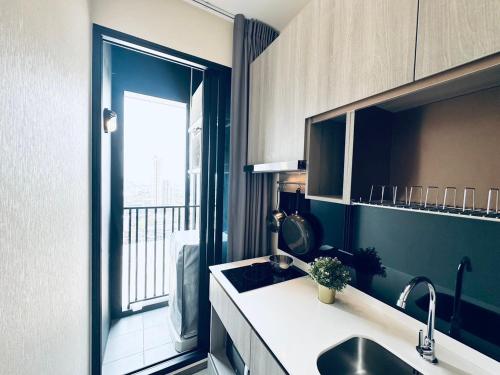 a kitchen with a sink and a large window at Modern condo nr BTS ONNUT WIFI in Bangkok