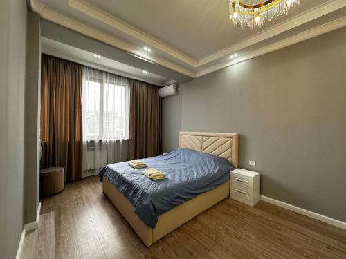 1 dormitorio con cama y lámpara de araña en Your home away from home., en Bishkek