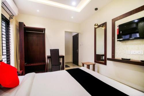 ein Hotelzimmer mit einem Bett, einem Schreibtisch und einem Spiegel in der Unterkunft HOTEL GRAND PALACE & BANQUET in Shiliguri