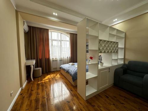 1 dormitorio con cama, escritorio y sofá en Your home away from home., en Bishkek