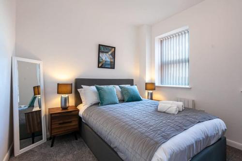 ein Schlafzimmer mit einem großen Bett und einem Spiegel in der Unterkunft Modern 2 Bedroom Apartment in Bolton in Bolton