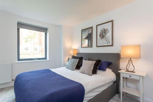 a bedroom with a blue and white bed and a window at Luxurious 1 bed apartment with free parking in York