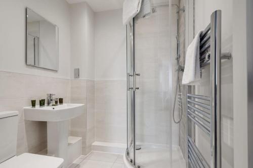 a white bathroom with a shower and a sink at Beautiful 2 Bed Apartment in a Converted Mill in Leeds