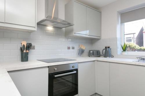 a kitchen with white cabinets and a stove top oven at Stunning 2 Bedroom Apartment in Wallasey in Wallasey