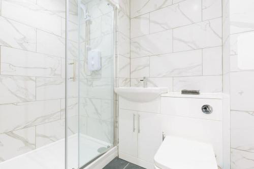 a white bathroom with a shower and a sink at Central Ipswich Modern Budget 1 Bed Apartment in Ipswich