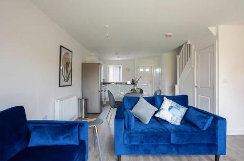 uma sala de estar com um sofá azul e uma cozinha em Lovely brand new 3 bedroom city centre house with garden em Derby
