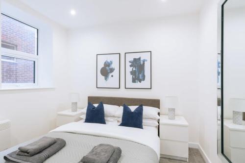 a white bedroom with a large bed with blue pillows at Central Ipswich Modern Budget 1 Bed Apartment in Ipswich