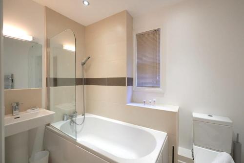 A Stylish Apartment with Parking in Preston في بريستون: حمام مع حوض أبيض ومغسلة