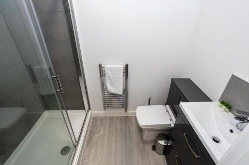 a bathroom with a shower and a toilet and a sink at Contemporary Bolton Apartment in Central Location in Bolton