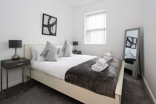 a bedroom with a large bed with a mirror at Contemporary Bolton Apartment in Central Location in Bolton