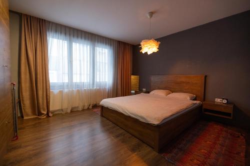 een slaapkamer met een bed en een groot raam bij Modern Bosnian home in Sarajevo