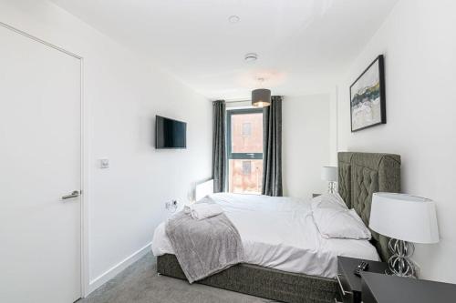 a white bedroom with a bed and a window at Stylish 2 Bedroom Apartment by Old Trafford in Manchester