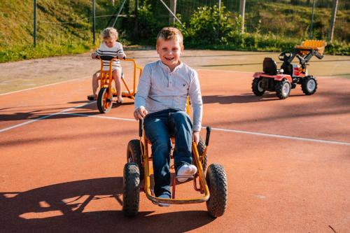 a young boy riding a toy tricycle on a court at Hotel Sperlhof in Windischgarsten