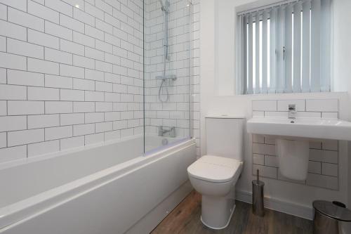 La salle de bains blanche est pourvue de toilettes et d'un lavabo. dans l'établissement Beautiful brand new 3 bedroom city centre house with garden, à Derby